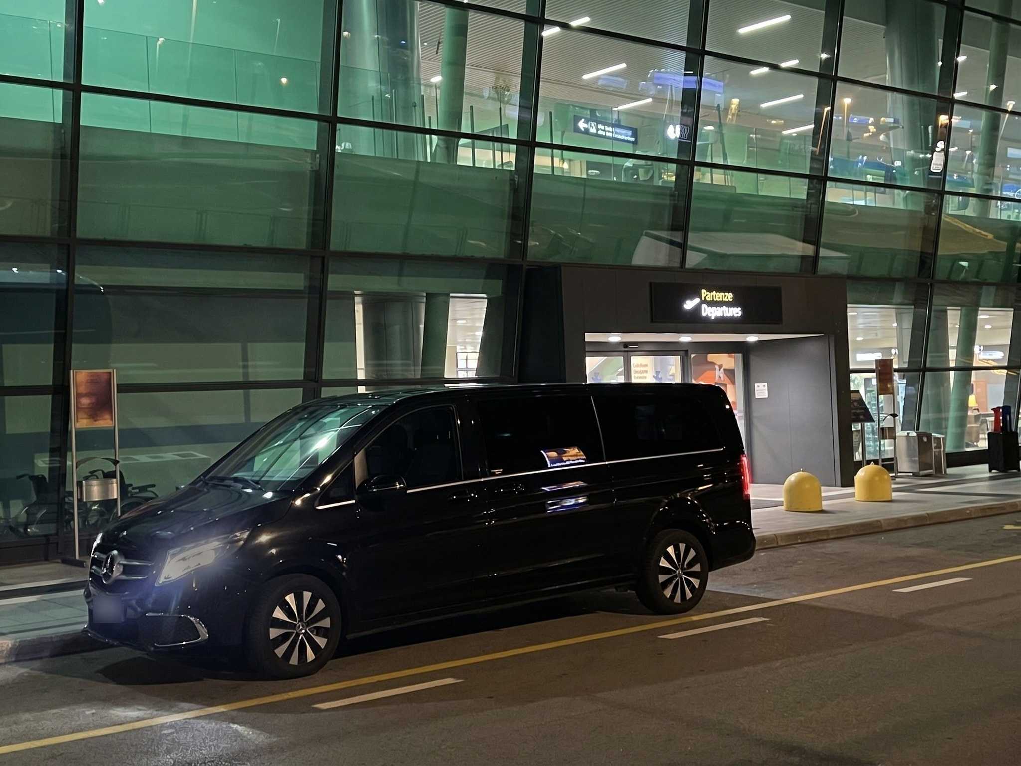 La nostra Mercedes Classe V nera di sera, a fari accesi, davanti all'ingresso Partenze dell'aeroporto di Verona